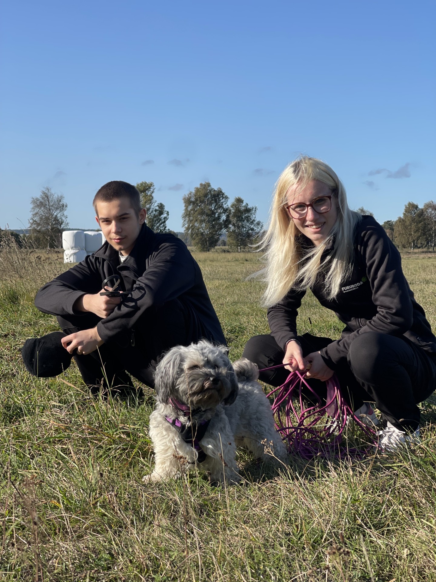 Två elever med hund i solskenet