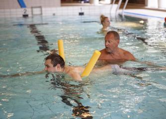 En person instruerar en annan i en simbassäng