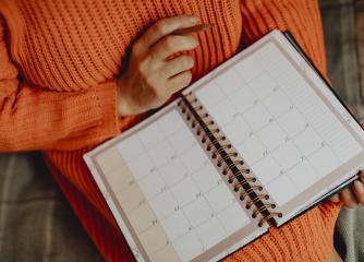 En person i orange tröja med en kalender i knät