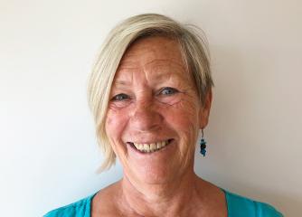 Kvinna med kort blont hår och turkos topp
